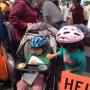 A young cyclist in a pretty new helmet checks her little brother’s fit.